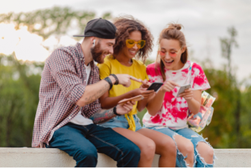 happy-young-company-smiling-friends-sitting-park-using-smartphones